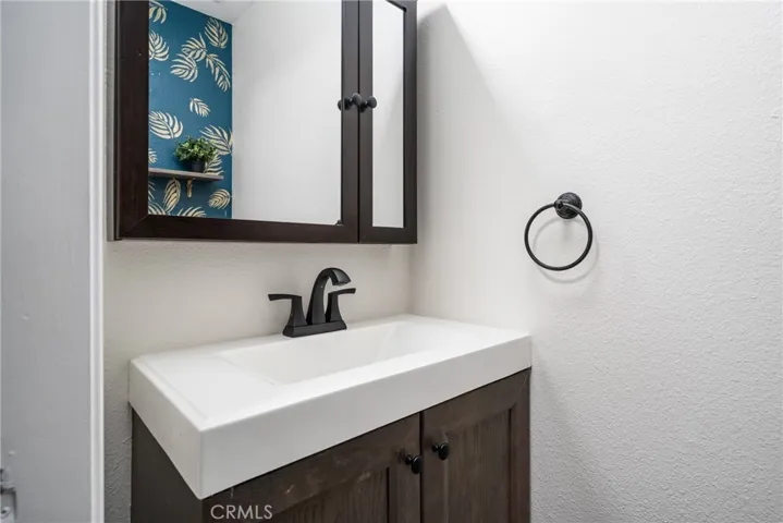 The downstairs ½ bath has a vanity with matte black finishes and a mirrored medicine cabinet.