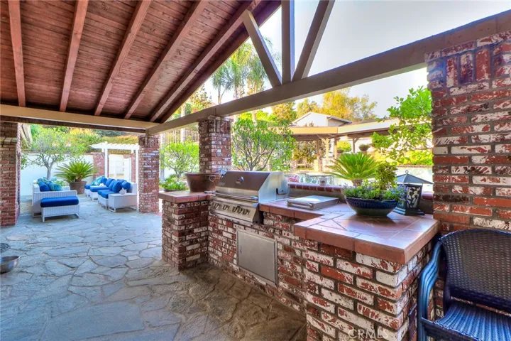 Outdoor kitchen, including beverage fridge, storage, tile counters, sink. Vaulted Patio ceiling .