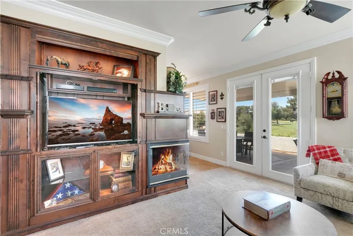 closer view of the custom entertainment center, fireplace and French doors to back patio