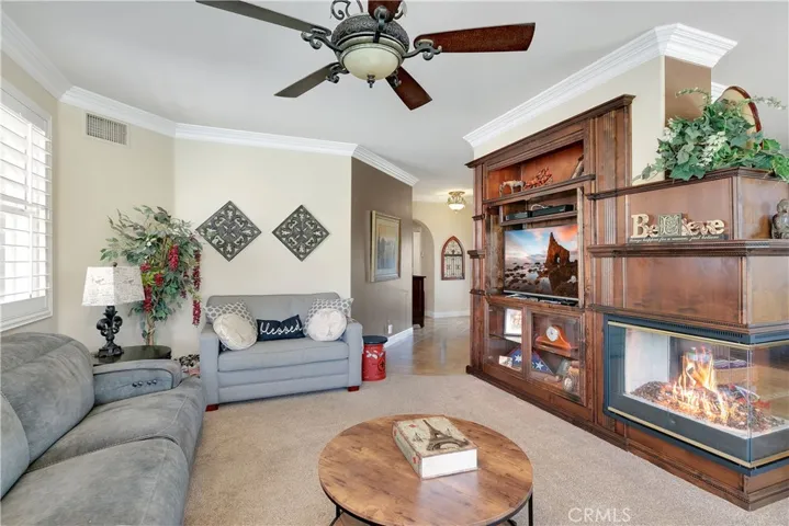 great room with custom cabinets, see-through fireplace and shows the crown molding which is throughout the home