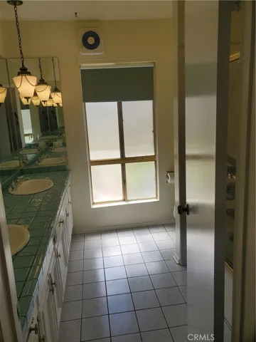 Hallway bath with double sinks & a tile floor