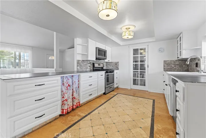 Stainless steel appliances included are the Whirlpool 5 burner gas range, the LG microwave range hood, stainless steel Fridgidaire dishwasher and white porcelain farm style sink.