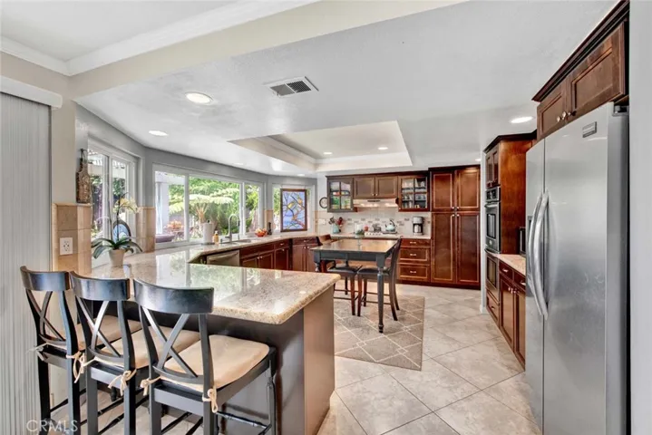 Breakfast Bar, Granite Countertops, Custom Cabinetry with Glass Display Panels and Pull-Outs, Stainless Appliances, and Center Island Dining Area