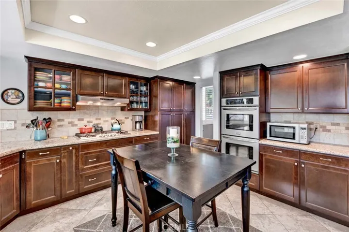Tray Ceiling with Recessed Lighting, Granite Countertops, Travertine Backsplash, Stainless Double Convection Ovens, Gas Cooktop, Double Wide Pantry with Pull-Outs