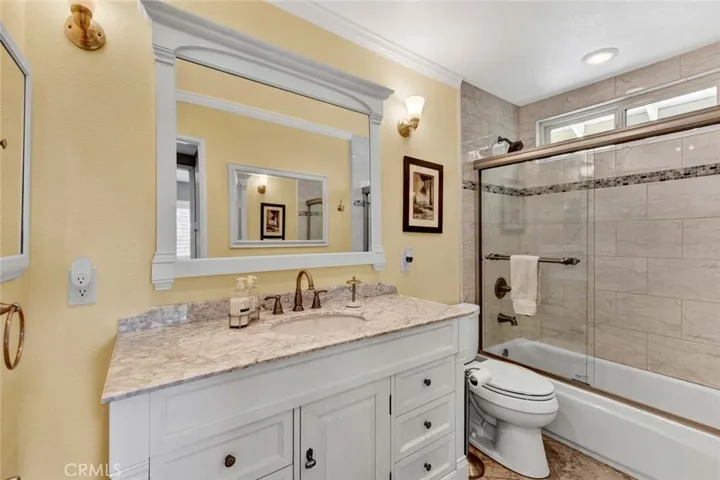 Remodeled Guest Bath with Newer Vanity with Marble Countertop, Tub/Shower Combo with Designer Tile Surround and Clear Glass Enclosure, Crown Moling, and Designer Fixtures