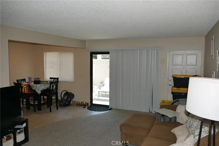 Living Room: opposite view towards patio & dining area, newer carpeting, tile flooring, view to patio, nice blinds throughout the unit.