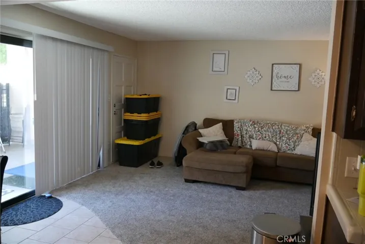 View to living room from entry, kitchen to right, dining area to left, newer carpeting, sliding door and single entry door from patio.