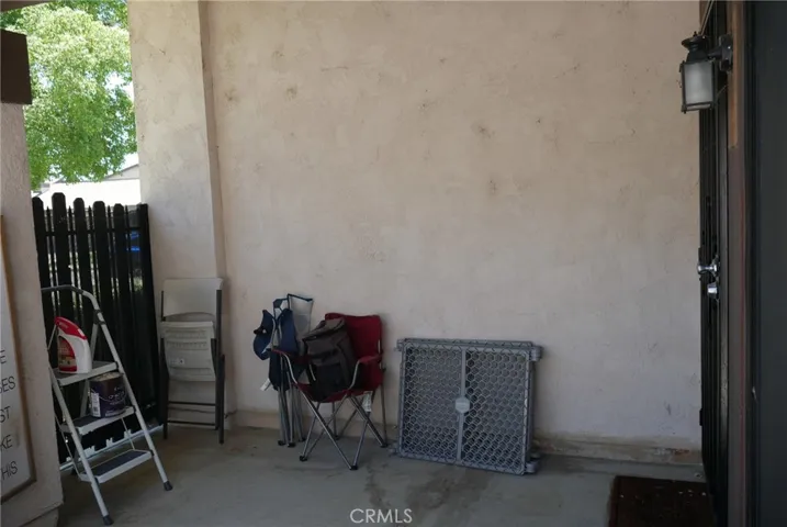 Patio: metal-framed entry gate to left, entry door to living room with security screen at right.