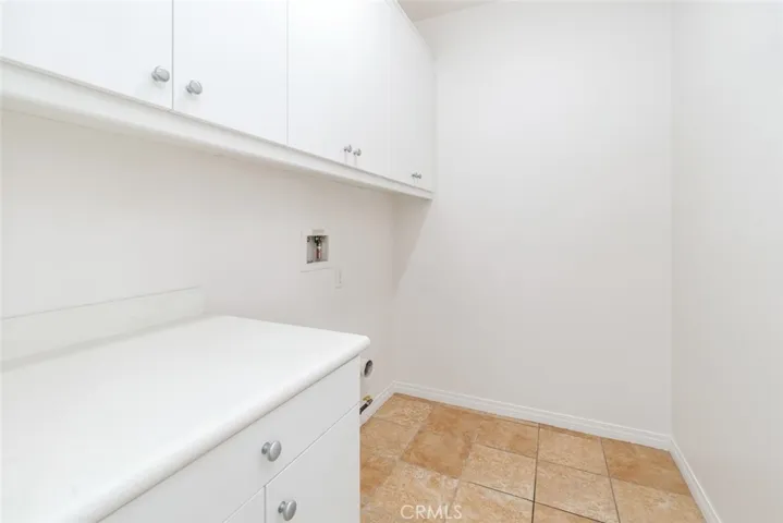 The laundry room offers plenty of cabinet storage space and a counter.