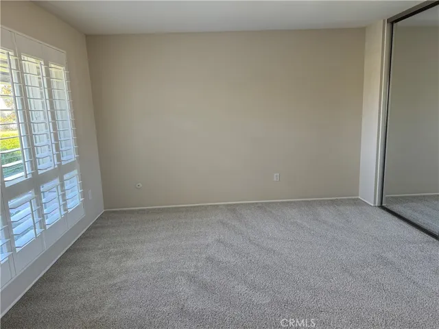 The primary bedroom has plantation shutters and mirrored closet doors.