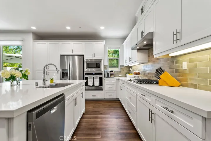 Spotless kitchen with full backsplash, stainless steel appliances, and plenty of storage