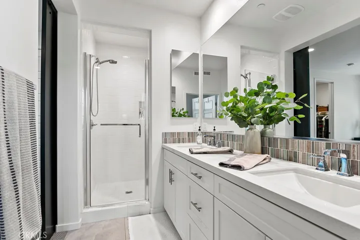 Primary bath features dual sinks, large walk-in shower with bench seat, and plentiful storage cabinetry