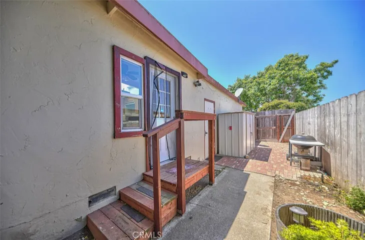 North side of house with view to the kitchen door and garage door and laundry shed outside.
