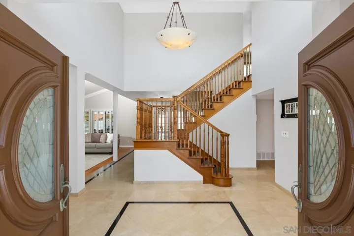 Welcome in to a double door entrance to a grand staircase.