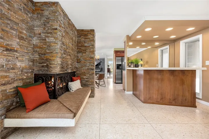 This family room/den will invite your family to gather and relax. The cozy fireplace has built in hearth seating. Whether binge-watching Netflix or hosting Super Bowl, this family room will accommodate your gatherings. Note the built in bar has direct access to the kitchen beyond. Floor to ceiling French windows overlook the sparkling pool.