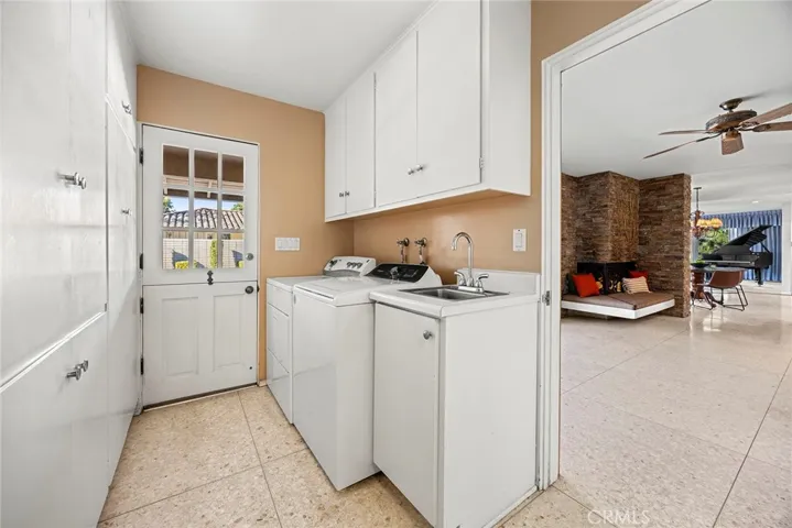 Laundry feels less of a chore in this laundry room. Space for side by side washer and dryer, a utility sink and walls with built in wood cabinets for ample storage. It is convenient for removing shoes after gardening or outdoor play. Charming Dutch door leads to the pool.