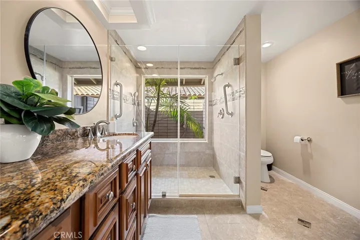 Updated grand shower has bench seating, glass enclosure and a large window with views to the private courtyard.