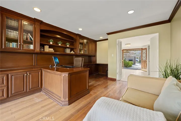 The centerpiece of the office is a built-in wood desk, offering ample workspace for a computer, documents, and other essentials.  The custom wood shelves create plenty of room for books, decor, and storage baskets to keep everything tidy.