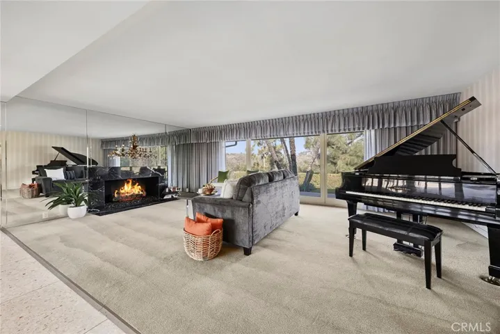 A wall of windows offer a breathtaking view of the outdoors. Living room fireplace has a stunning marble surround. The warmth and ambience of the fireplace makes this grand living room warm and welcoming. It is so spacious, it still feels roomy, even with a grand piano in it.