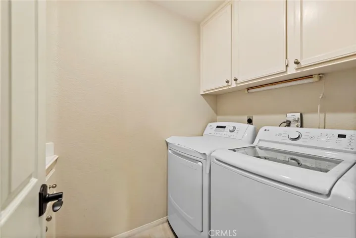 Interior laundry room with a sink and additional cabinets behind the door.
