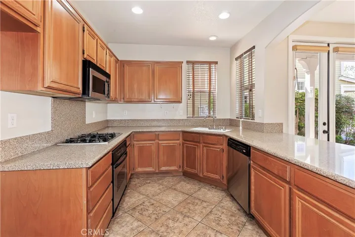 Warm kitchen cabinets, newer refrigerator not shown, stone counters.