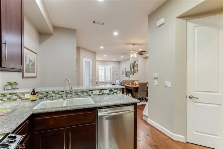Another View of Kitchen with Beautiful Cabinetry, Granite Counter tops, Dual Sinks and Stainless Steel Dishwasher.  Pantry door is on the Right.