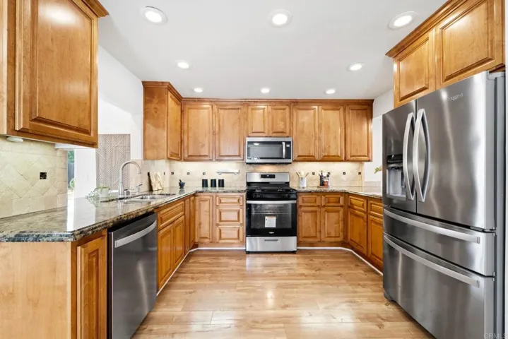 Kitchen features Whirlpool SS appliances & granite counters combining functionality & durability.