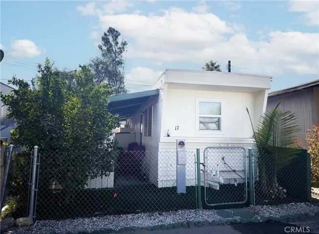 This picture shows the home's front exterior, which includes a palm tree and a fruit tree.