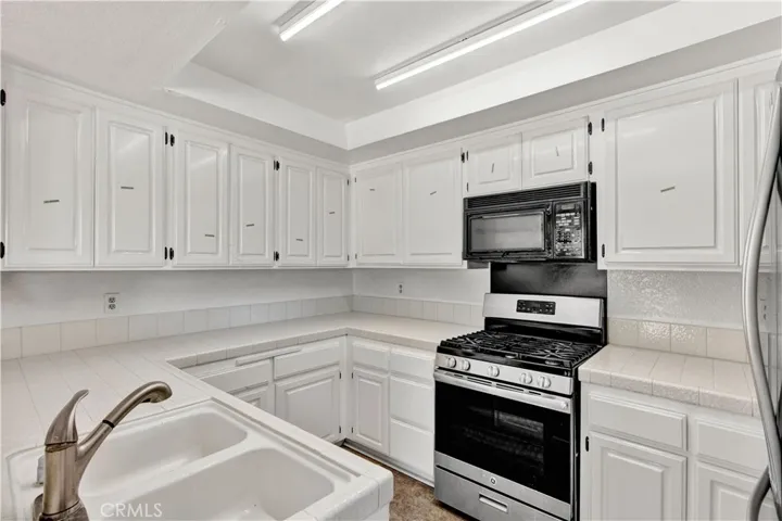 Bright White Kitchen has Tile Countertops, Tile Flooring, and New Cabinetry 
Doors