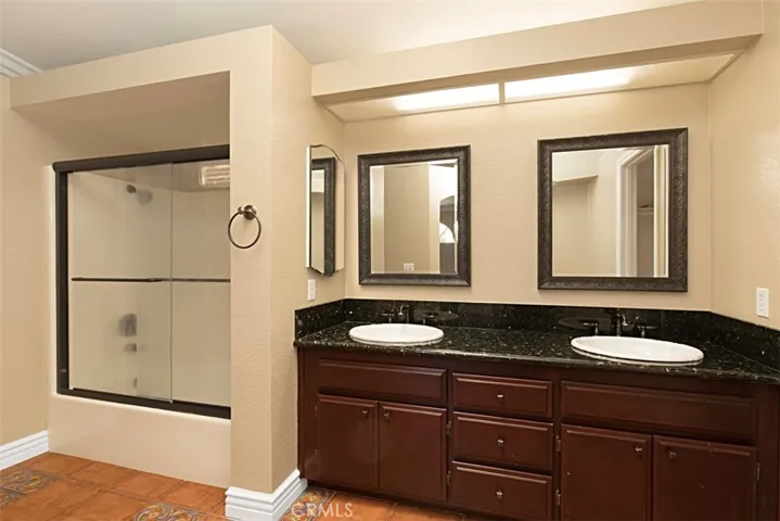 Upgraded dual-sink vanity & glass-enclosed soaking tub in shower in primary bathroom