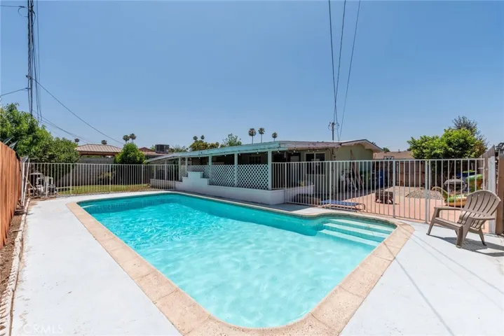 Pool enclosed by fencing and view of the large side yard.