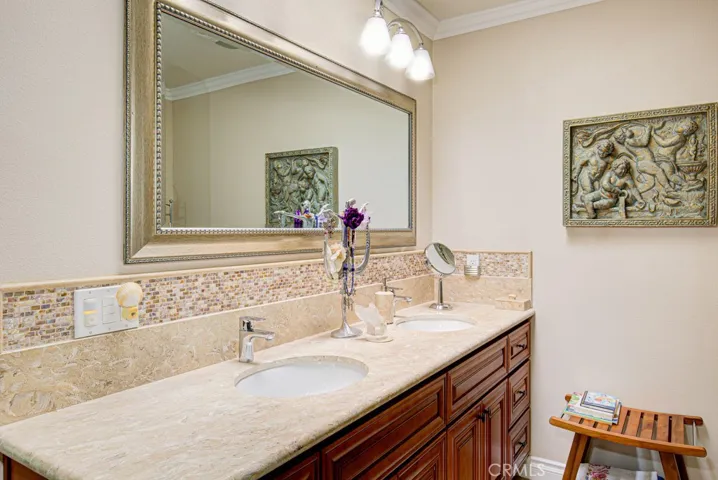 Primary bathroom has custom wood cabinetry, dual sinks and a marble countertop.