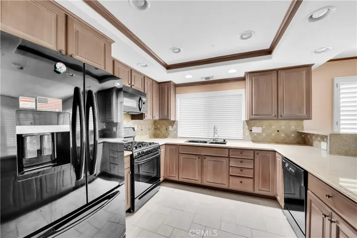 Kitchen Features Tile Flooring, Tray Ceiling with Recessed Lighting, Granite Countertops, Designer Tile Backsplash, and Custom Cabinetry