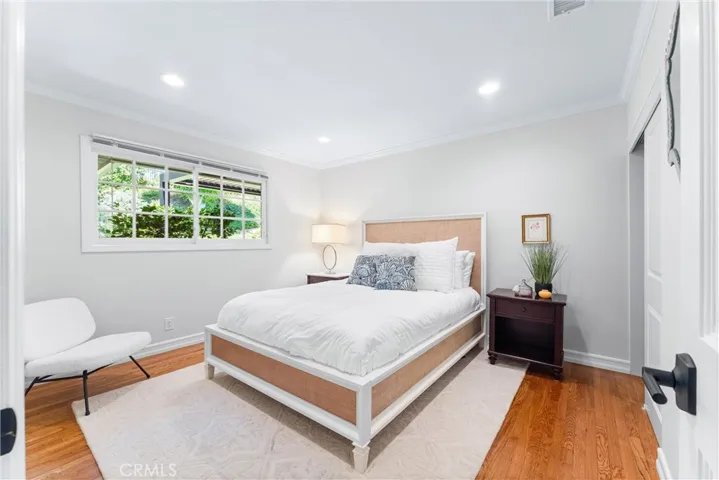 Guest bedroom is elegant and enchanting. It offers serene views of the yard, creating a comfortable and welcoming retreat.