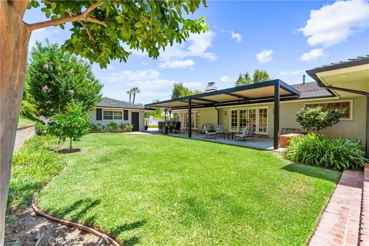 Backyard is a serene oasis. Blooming crepe myrtle tree and healthy manicured yard with automatic sprinkler system and automated patio cover by StruXture Pergola, that rotates to open and access sun or close for shade.
