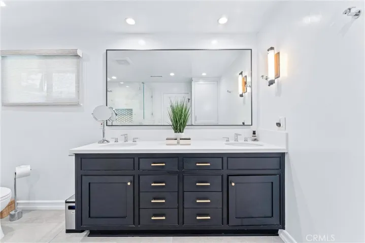 Primary bathroom with striking dual vanity takes centerstage. Expansive mirror and wall sconce highlight the brilliant lighting, making you and your spa-like retreat sparkle.