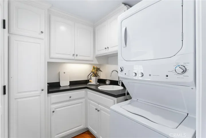 Mudroom | Laundry Room | Scullery Room  - adjacent to the kitchen you'll find a versatile room featuring a privacy/pocket door, complete with sink, custom cabinetry and stackable washer/dryer. There's also a separate  entrance to access the side yard.