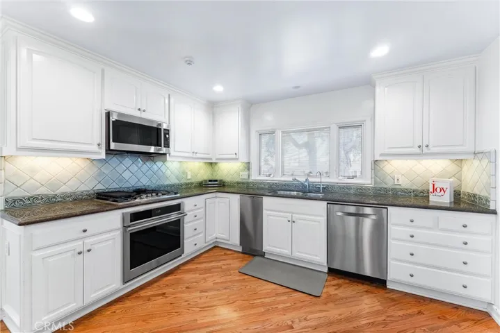 Kitchen is at the heart of the home featuring granite countertops, a tile backsplash, custom cabinetry with pull-out drawers and high-end stainless-steel appliances professional hood, a six-burner gas stovetop, double ovens, a convection microwave, a built-in Sub-Zero refrigerator, and a spacious center island.