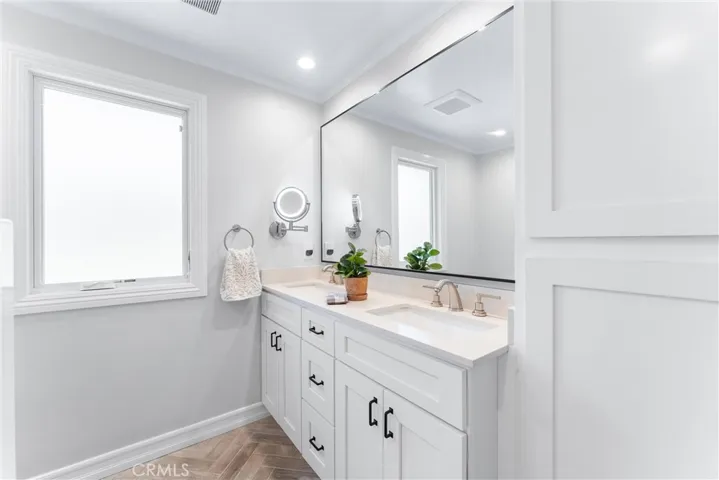 Fully remodeled bathroom with herringbone tiled floor, dual vanity with soft close drawers, linen cabinetry,  full bathtub & shower, with pivoting glass door. 
Shower door slides open for bathing little ones