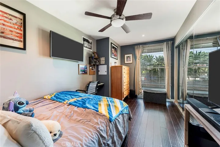 Bedroom 1 with smooth ceiling, ceiling fan and engineered flooring.
