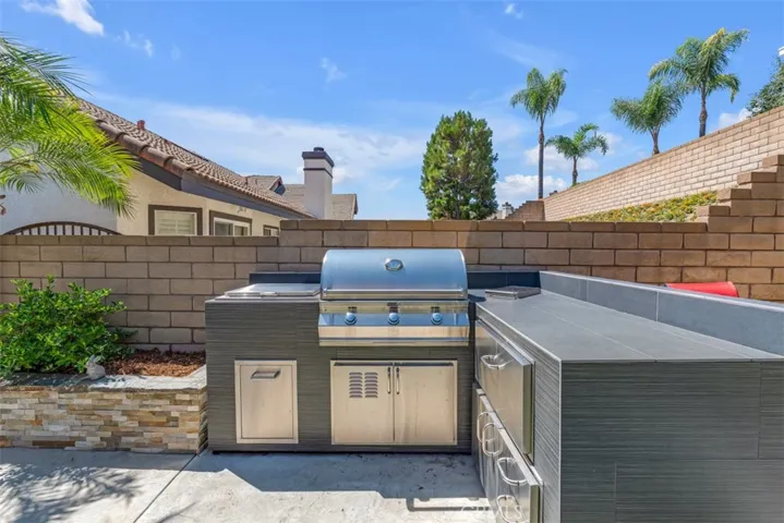 Outdoor island with a Fire Magic propane grill, side burner, cooler, plus storage