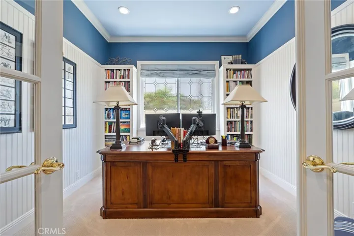 downstairs dedicated office with double French doors, custom Cabinents and wall detailing, crown molding, recessed lights, custom window coverings, and beveled glass.