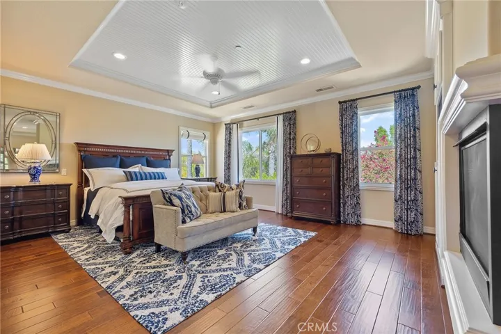 Master bedroom with dual sided fireplace, wood detail ceiling, recessed lighting, crown molding, built in cabinets and gorgeous wood floors.