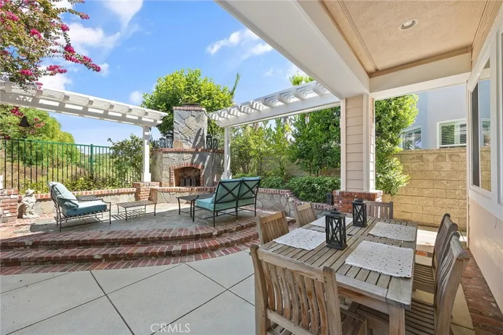 covered patio and raised stone seating area surrounding a wood burning fireplace.