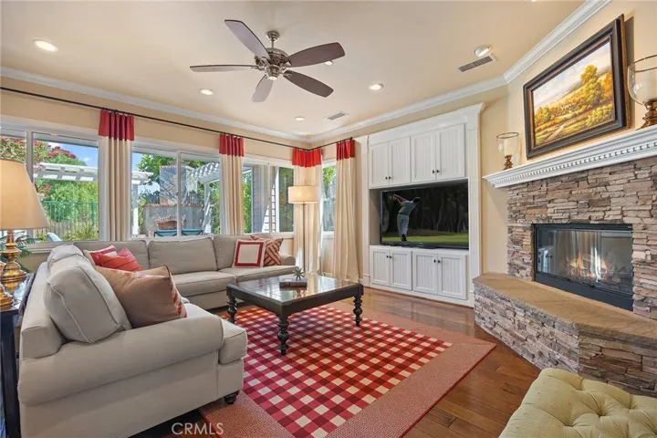spacious family room with built in cabinets, stone wood burning fireplace, custom window coverings, recessed lighting and ceiling fan. Notice the high ceilings throughout.