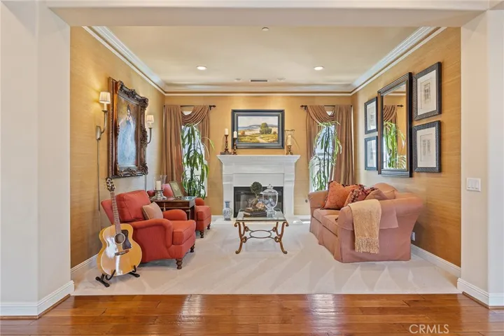 separate living / sitting room with fireplace, crown molding, sconces, recessed lights and custom wallpaper and window covering.  Elegant, symmetrical design