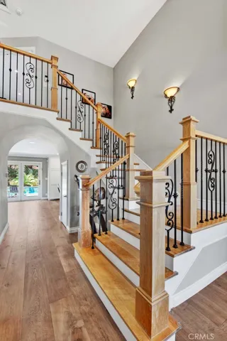 Gorgeous Alder Wood Staircase with Wrought Iron Railing and Sconce Lighting