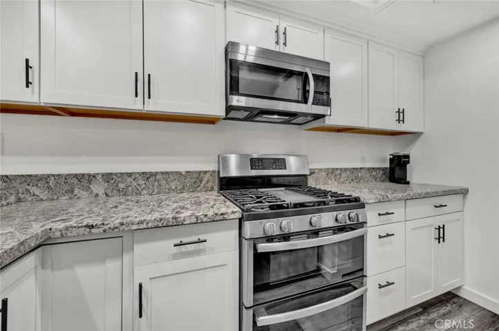 Granite counters in kitchen, double oven, white shaker cabinets, stainless steel appliances.