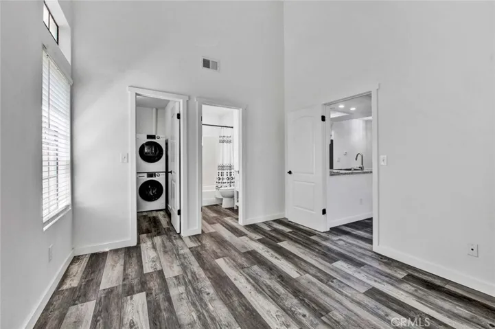 View from 1st bedroom into walk-in closet, bathroom and kitchen. Vaulted ceilings and trees view from window.