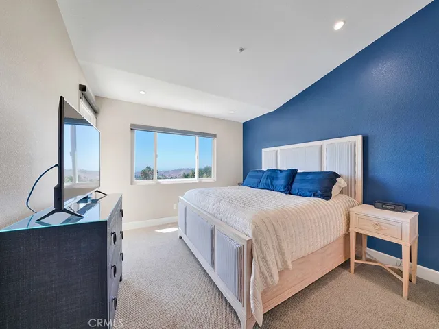 The primary bedroom features vaulted ceilings,  a balcony and direct panoramic ocean, Catalina Island, hillside views and more.